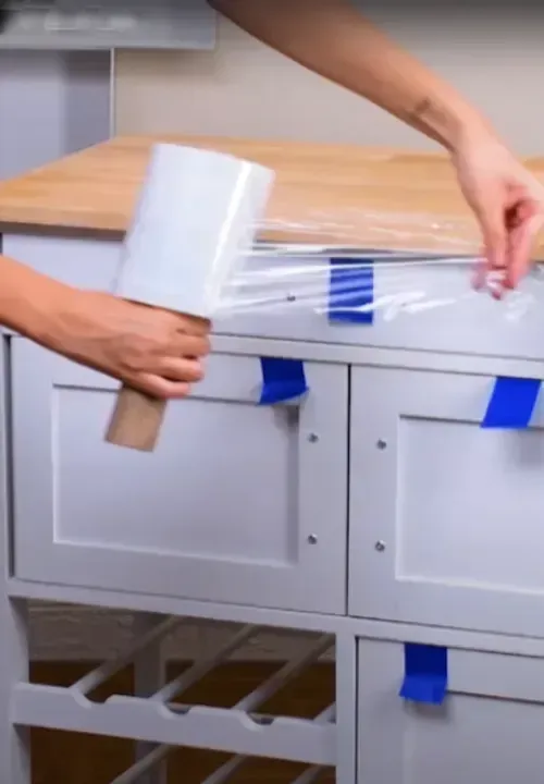 Mover stretch-wrapping the drawers of a white cabinet